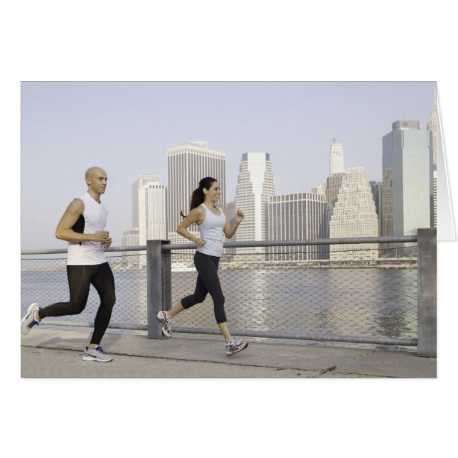 Couple running on pier with city in background (Front Horizontal)