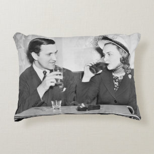 Couple sitting together in a restaurant flirting w decorative cushion