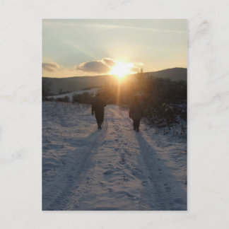 Couple walking in the snow at sunset postcard