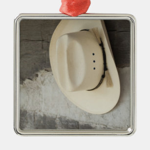 Cowboy hat hanging on wall of log cabin metal ornament