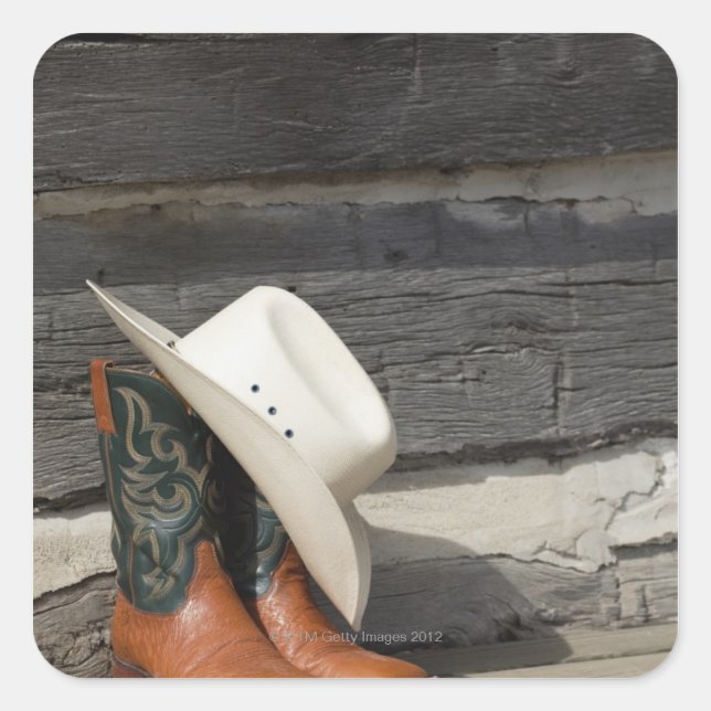 Cowboy hat on cowboy boots outside a log cabin square sticker (Front)