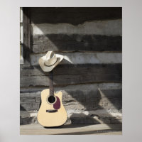Cowboy hat on guitar leaning on log cabin