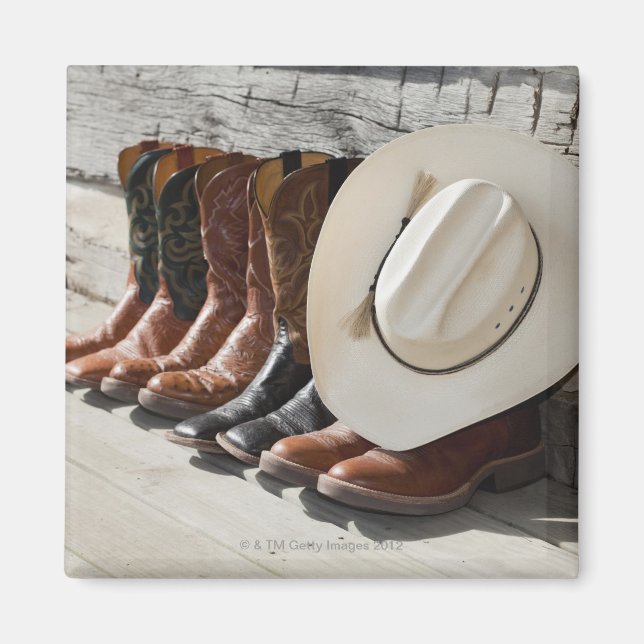 Cowboy hat on row of cowboy boots outside a log magnet (Front)