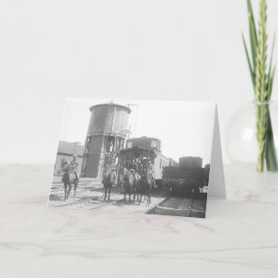 Cowboys on horses posing in front of a train card