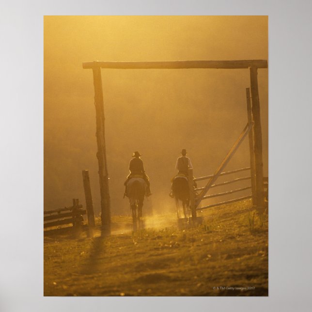 Cowboys riding through gate at dusk poster (Front)