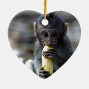 Cute baby macaque monkey eating banana ceramic tree decoration