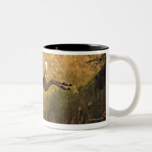 Deer leaping through field Two-Tone coffee mug