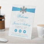 Diamante Snowflake & Blue Ribbon Winter Wedding Pedestal Sign<br><div class="desc">The diamanté snowflake & blue ribbon wedding collection is perfect for any couple planning a romantic winter wedding celebration. The design features a light silvery grey and white snowflake textured background with a diamanté snowflake on top of a silky looking ribbon. The wording incorporates the same silvery grey and blue...</div>