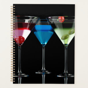 Different cocktails in martini glasses on black planner