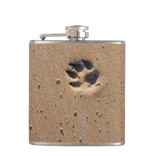 Dog paw prints on a sandy beach hip flask