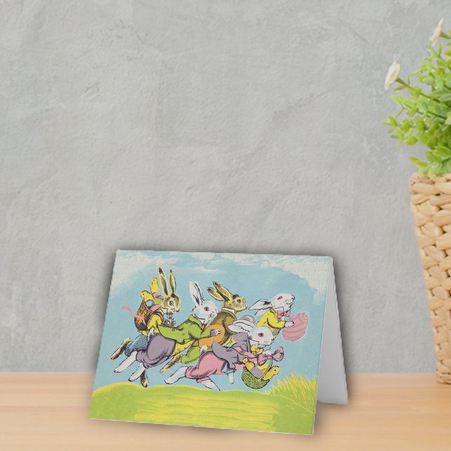 Easter Running Rabbits Pastels Holiday Card (Group running Easter rabbits in pastel clothes eggs baskets in grass under blue sky on notecard.)