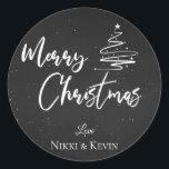 Elegant Chalkboard Script Merry Christmas Tree Classic Round Sticker<br><div class="desc">Elegant Chalkboard Script Merry Christmas Tree Classic Round Sticker. Customise it by changing the names  . The design has Merry Christmas written in pretty font on a chalkboard background along with the names of the couple.  For any further customisation ,  feel free to contact me at mypaperlove2021@gmail.com</div>