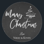 Elegant Chalkboard Script Merry Christmas Tree Classic Round Sticker<br><div class="desc">Elegant Chalkboard Script Merry Christmas Tree Classic Round Sticker. Customise it by changing the names  . The design has Merry Christmas written in pretty font on a chalkboard background along with the names of the couple.  For any further customisation ,  feel free to contact me at mypaperlove2021@gmail.com</div>