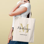 Elegant Gold Black Monogram Bridesmaid Tote Bag<br><div class="desc">Timeless glamour meets classic elegance with this tote featuring a gold monogram initial layered with a personalised name in sophisticated black script and the bridal party role below. A luxe monogram keepsake with a warm golden glow that elevates any wedding celebration. Name,  initial,  and role are fully customisable.</div>