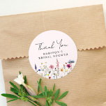 Elegant Wildflower Pink Bridal Shower Thank You Classic Round Sticker<br><div class="desc">Elegant floral bridal shower thank you stickers featuring a bottom border of watercolor wildflowers and foliage in shades of pink, yellow, purple, blue, and green on a blush pink background. Personalise the wildflower bridal shower thank you stickers with the bride-to-be's name. The personalised wildflower stickers are perfect for spring and...</div>