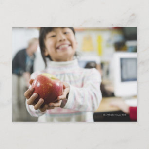 Elementary student holding an apple in her hand postcard
