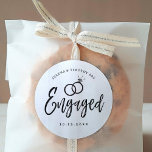 Engagement Party Script Lettering | Classic Round Sticker<br><div class="desc">A fun and unique script lettered sticker tailored specifically to you an engagement party.  It features the word "engaged" with wedding rings resting over it. Underneath this and above it are the names of the bride and groom and the engagement date.</div>