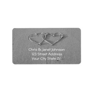 Entwined hearts in beach sand address labels