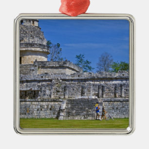 Family of tourists walk past ancient Mayan Metal Tree Decoration