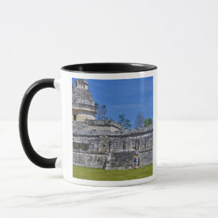 Family of tourists walk past ancient Mayan Mug