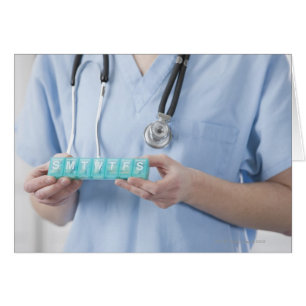 Female doctor holding pill box, mid section