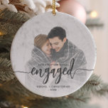 First Christmas Engaged Photo Grey Script Ceramic Ornament<br><div class="desc">Commemorate your engagement with this beautiful modern keepsake ornament. The charcoal grey text reads "Our first Christmas engaged, " with the word "engaged" in bold handwriting script with flourishes before and after. Replace the sample image with your favourite photo, and add your names and the year. A white gradient filter...</div>