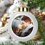 First Christmas Engaged Photo Modern White Script Ceramic Ball Christmas Ornament<br><div class="desc">Commemorate your engagement with this beautiful modern keepsake ornament. The white text reads "Our first Christmas engaged, " with the word "engaged" in elegant calligraphy script with decorative swashes before and after. Replace the sample image with your favourite photo, and add your names and the year. A dark gradient filter...</div>
