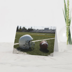 Football and football helmet on football field card
