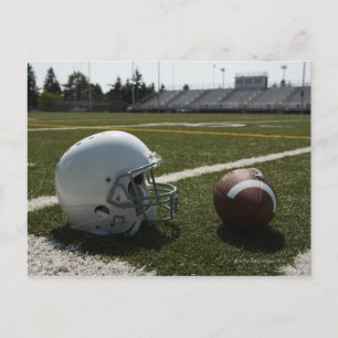Football and football helmet on football field postcard