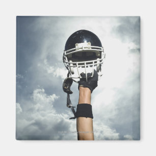 Football player holding helmet in air magnet