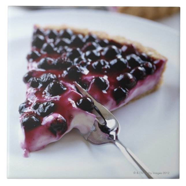 Fork slicing blueberry pie on plate tile (Front)