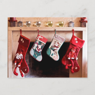 Four Christmas stockings hanging on fireplace Holiday Postcard