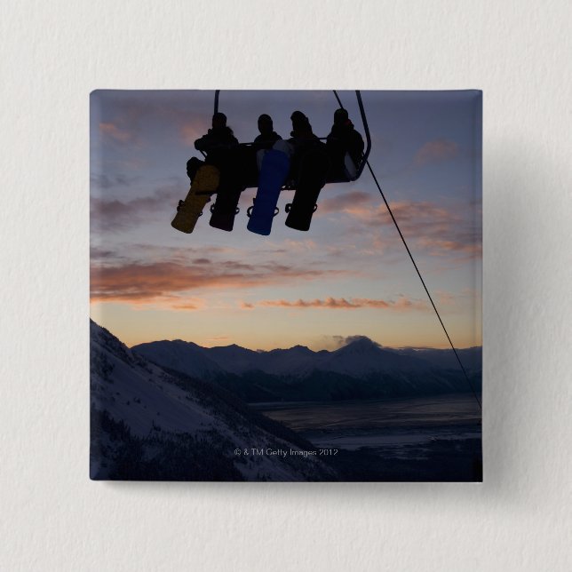 Four snowboarders are silhouetted on a ski lift 15 cm square badge (Front)