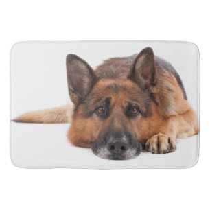 German shepherd lying down on a white background bath mat