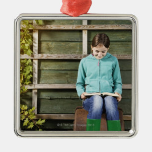 Girl sitting and reading book near vine metal ornament
