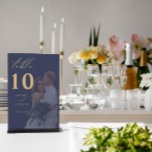 Gold Calligraphy Navy Photo Wedding Table Number<br><div class="desc">The wedding table number card features a prominent number “10” in an elegant red font at the centre. The left side of the card is adorned with a beautiful floral design in shades of blue, red, and grey, complemented by green foliage. The white background enhances the vibrant colours, making this...</div>