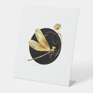 Golden dragonfly in black circle pedestal sign
