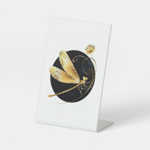 Golden dragonfly in black circle pedestal sign