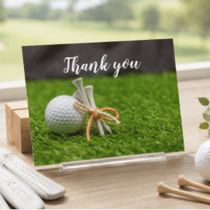 Golf ball and tee are on green grass thank you postcard