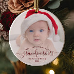 Grandparents First Christmas Photo Red Script Ceramic Ornament<br><div class="desc">Help them celebrate their first grandchild with this beautiful modern keepsake ornament. The burgundy red text reads "Our first Christmas as grandparents, " with the word "grandparents" in elegant handwriting script with flourishes before and after. Easily replace the sample image with your favourite photo of the new baby, and add...</div>