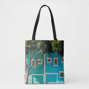 Green and blue houses beside trees on sidewalk tote bag