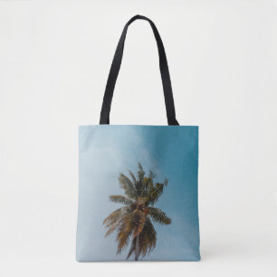 Green coconut tree under blue sky tote bag