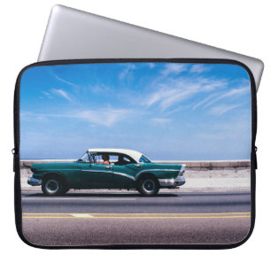 Green coupe on grey asphalt road laptop sleeve