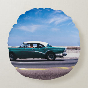 Green coupe on grey asphalt road round cushion