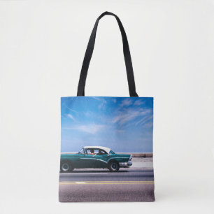 Green coupe on grey asphalt road tote bag