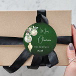 Green gold white baubles Christmas Classic Round Sticker<br><div class="desc">For a Christmas party favours or gift wrapping. A rustic green uneven coloured background. Decorated with white and gold baubles and some greenery and a pine cone.  Personalise and add your name,  year.  Text: Merry Christmas</div>