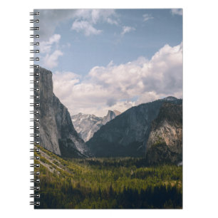 GREEN GRASS FIELD NEAR ROCKY MOUNTAIN UNDER WHITE NOTEBOOK