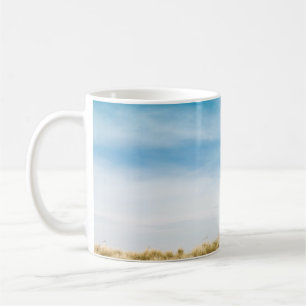 Green grass field under blue skies coffee mug