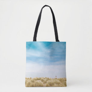 Green grass field under blue skies tote bag
