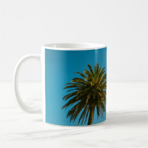 Green palm tree under blue sky in the morning coffee mug